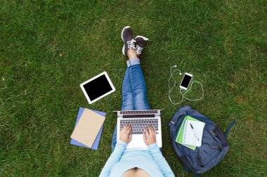 lány ül a zöld fűben laptop