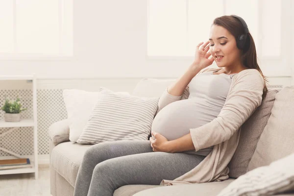 Беременная женщина слушает музыку в наушниках — стоковое фото