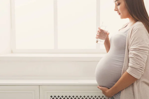 Mujer embarazada bebiendo agua en la ventana — Foto de Stock