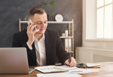 Smartphone çalışma evinde konuşurken erkek ofis çalışanı
