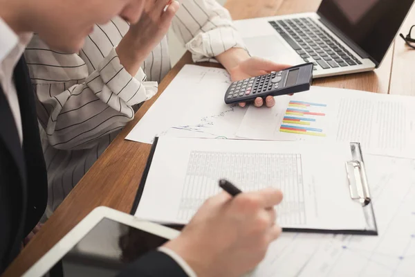 Compañeros de negocios revisando documentos y usando la calculadora — Foto de Stock