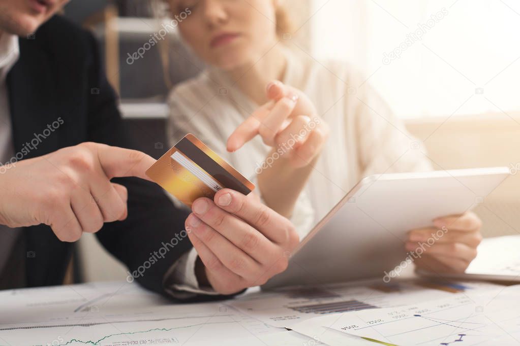 Business colleagues using tablet and holding credit card