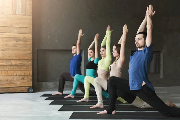 Молодые женщины и мужчины в классе йоги, расслабиться медитации позы — стоковое фото