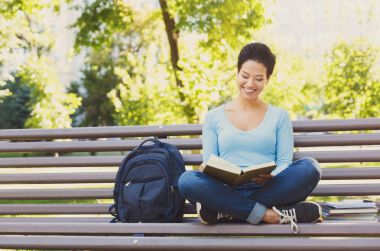 Dışarıda kitap okuyan genç bir kadın.