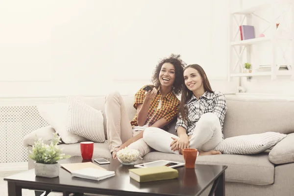 Lächelnde Freundinnen, die zu Hause fernsehen — Stockfoto