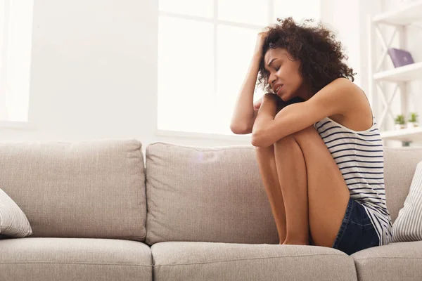Sorgliga afroamerikansk kvinna på soffan hemma — Stockfoto