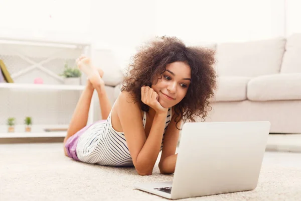 Menina sorrindo jovem com laptop deitado no chão — Fotografia de Stock