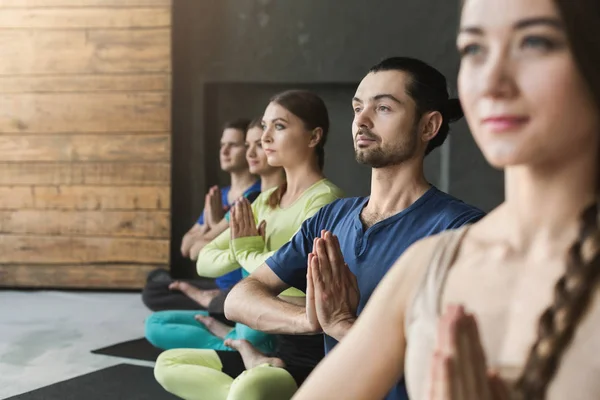 Mujeres jóvenes y hombres en clase de yoga, relajar la meditación pose — Foto de Stock