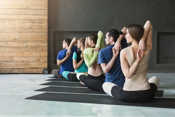 Mujeres jóvenes y hombres en clase de yoga, relajar la meditación pose — Foto de Stock