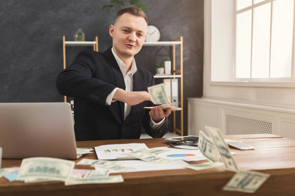 Financier man sitting in office and holding money in hand