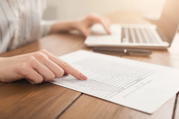 Primer plano de las manos de la mujer escribiendo en el ordenador portátil y comprobando los papeles —  Fotos de Stock