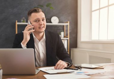 Smartphone çalışma evinde konuşurken erkek ofis çalışanı