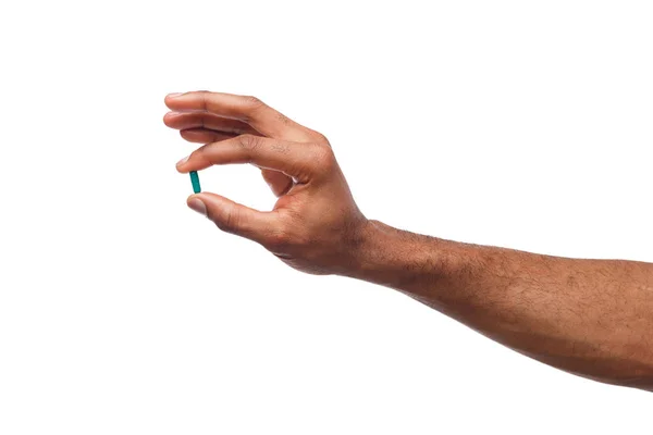 Mano negra sosteniendo una píldora aislada sobre fondo blanco — Foto de Stock
