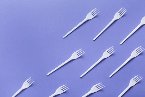 Vista dall'alto su forchette di plastica su sfondo viola — Foto Stock