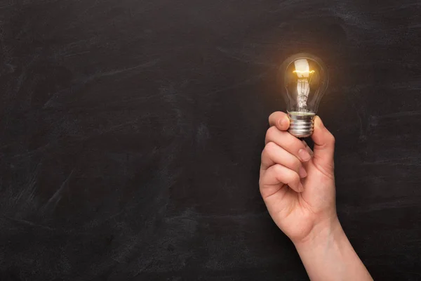 Glowing light bulb in hand at black background — Stock Photo, Image