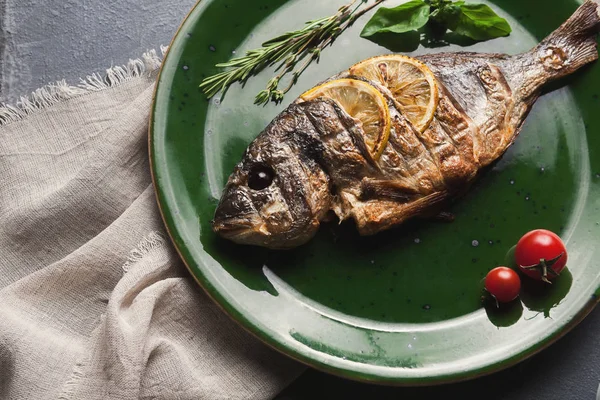 Whole grilled dorado with lemon slices on plate — Stock Photo, Image