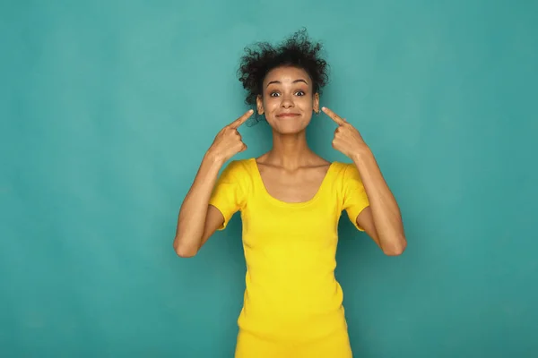 Sorrindo menina olhando e apontando para os ouvidos — Fotografia de Stock