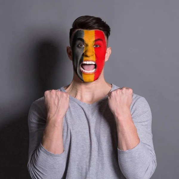 Young man with Belgium flag painted on his face