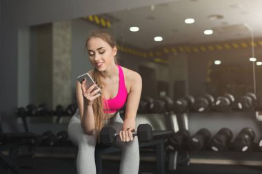 Spor salonunda cep telefonu kullanan genç kız