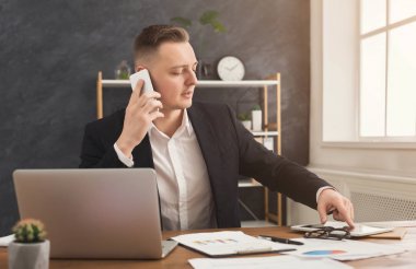 Smartphone çalışma evinde konuşurken erkek ofis çalışanı
