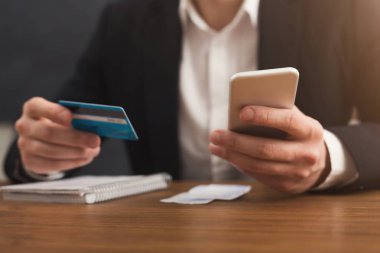 Bir kredi kartı tutan ve smartphone kullanarak eller mans