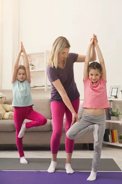 Young woman and daughters doing yoga exercise at home — Stock Photo, Image