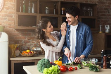 Mutlu çift birlikte yemek pişiriyor.