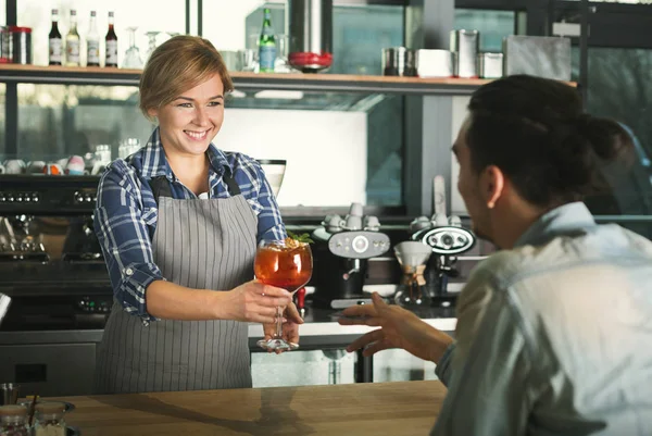 Smiling barista taking payment from client
