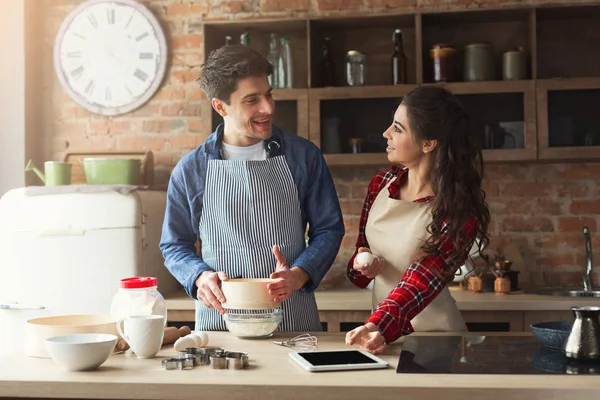 Счастливые молодые женщина и мужчина, пекущие на мансардной кухне — стоковое фото