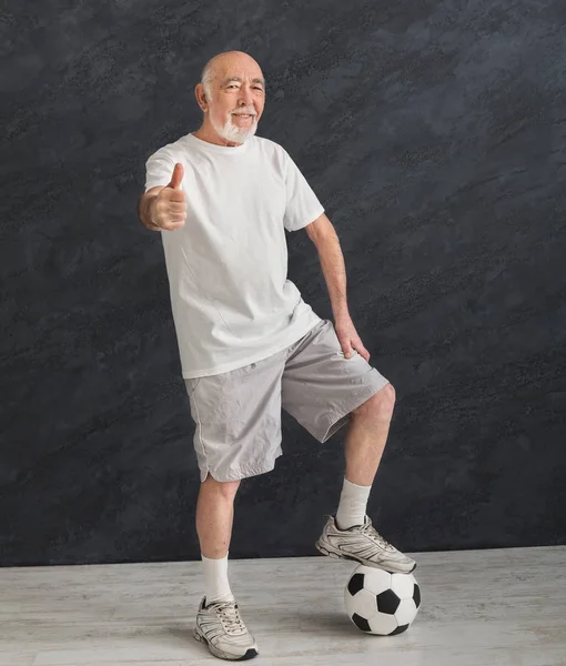 Hombre mayor con pelota de fútbol mostrando el pulgar hacia arriba — Foto de Stock