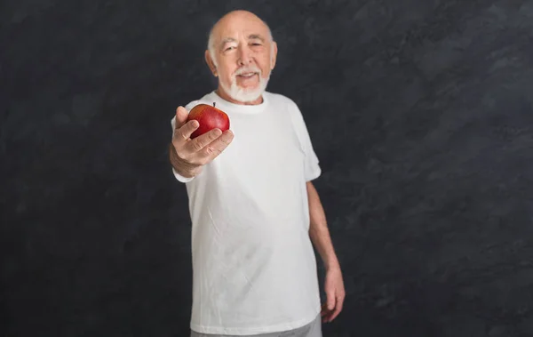 Glücklicher Senior, der Ihnen einen roten Apfel anbietet — Stockfoto