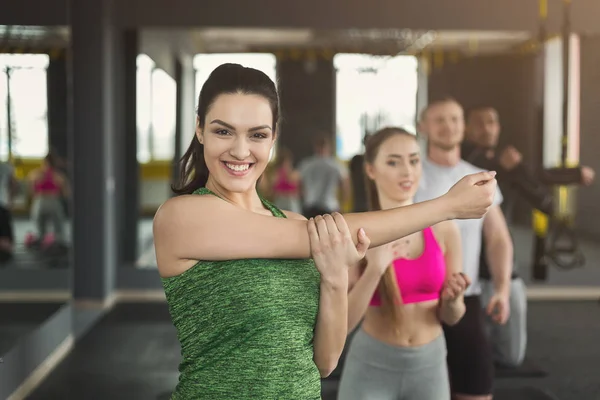 Jovem mulher se aquecendo antes do treinamento em ginásio — Fotografia de Stock