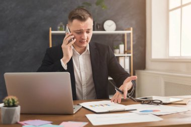 Smartphone çalışma evinde konuşurken erkek ofis çalışanı
