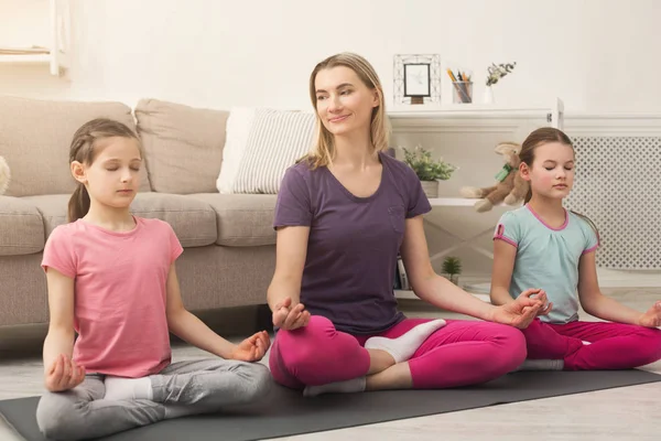 Young woman and daughters doing yoga exercise at home — Stock Photo, Image