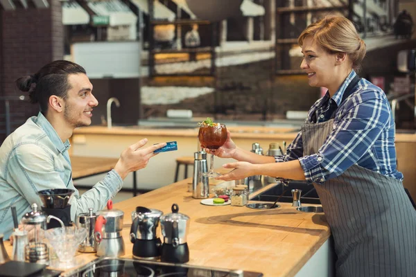 Lachende barista nemen betaling van client — Stockfoto