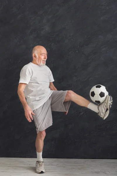 Старший чоловік штовхає футбольний м'яч в приміщенні — стокове фото