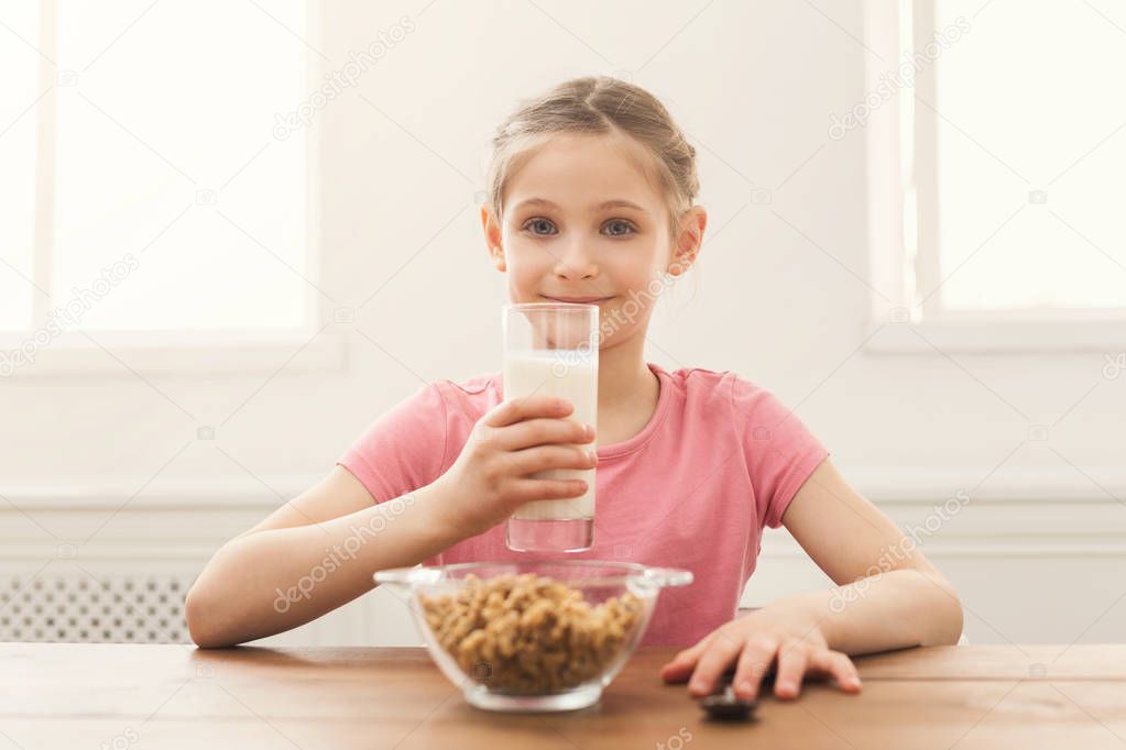 Happy child girl drinking milk