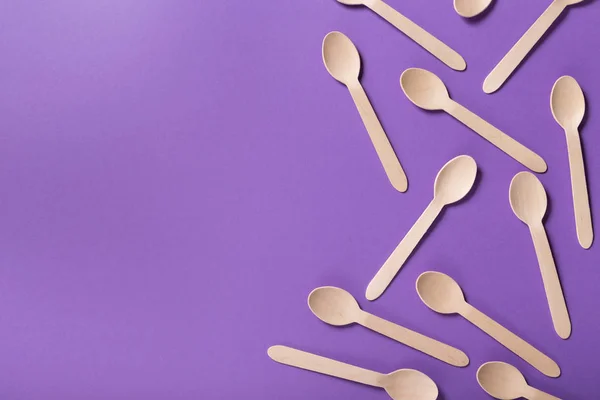 Many wooden spoons on purple background, top view — Stock Photo, Image