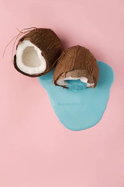 Pintura azul saindo do coco no fundo rosa — Fotografia de Stock
