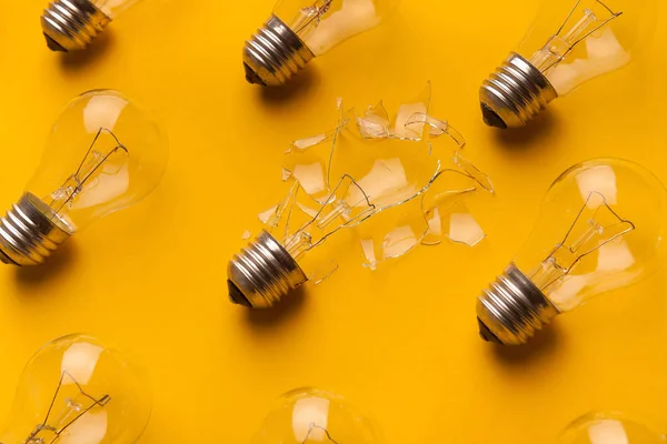 Celku a rozbité žárovky na žlutém podkladu — Stock fotografie