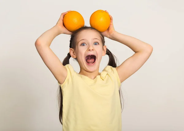 Menina feliz se divertindo com laranjas sobre fundo branco — Fotografia de Stock