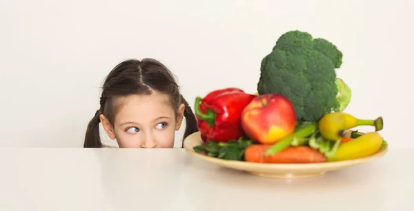Мила дівчинка дивиться на свіжі овочі — стокове фото