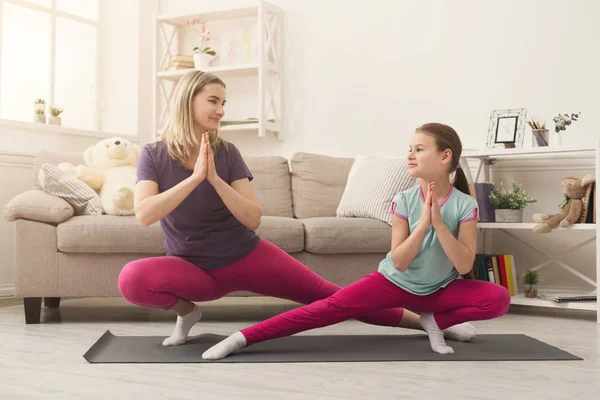 Young woman and child daughter doing yoga exercise at home — Stock Photo, Image