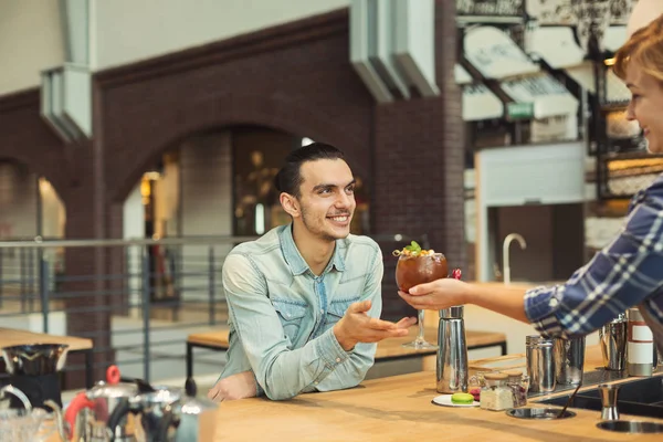 Ervaren lachende barista koffie geven aan klant — Stockfoto
