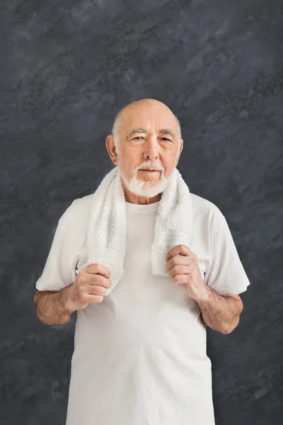 Zelfverzekerde senior man in sportkleding met handdoek — Stockfoto