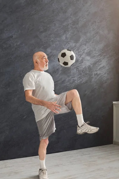 Hombre mayor pateando pelota de fútbol en el interior — Foto de Stock