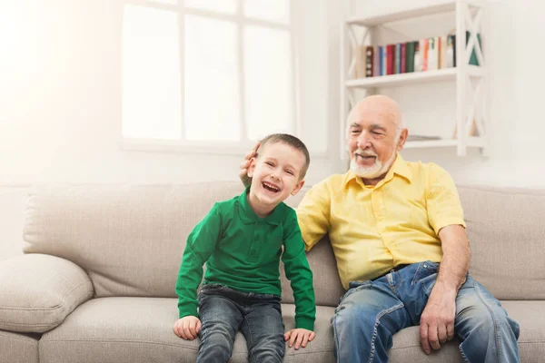 Liten pojke sitter på soffan med hans farfar — Stockfoto