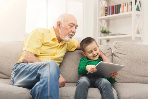 Старший мужчина смотрит видео на планшете с внуком — стоковое фото