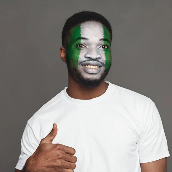 Young man with Nigeria flag painted on his face