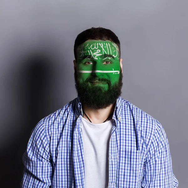 Young man with Saudi Arabian flag painted on his face